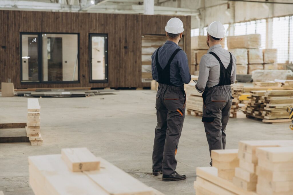 Construction workers inspecting modular building in factory